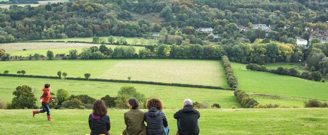 Adults sit and enjoy the view of green fields