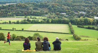 Adults sit and enjoy the view of green fields