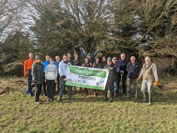 Volunteers holding up a Hedgerow Heroes banner near planted hedgerows