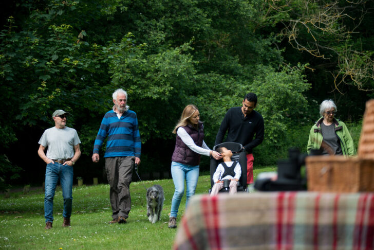 A group of people walking in their local park with a picnic table in the foreground