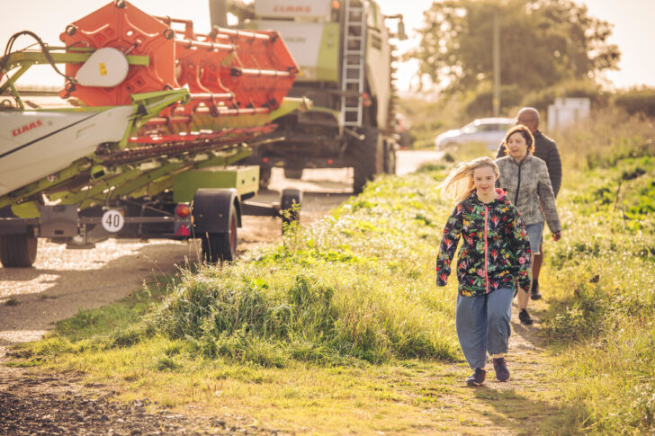 A family walking past some farming machinery in the countryside