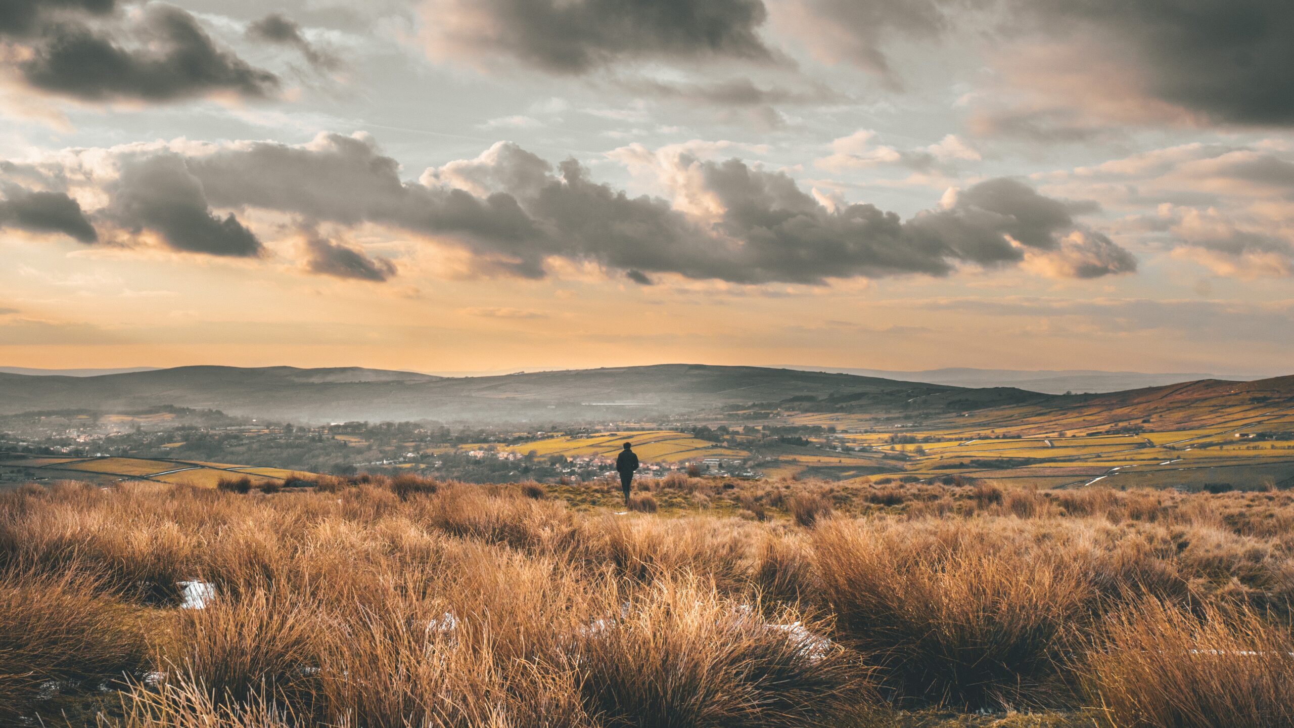 Distant figure stands in frosty scene looking over moorland