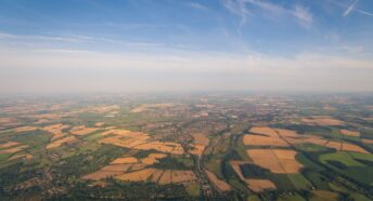 A wide horizon view of sky and fields with hedgerows and farmland