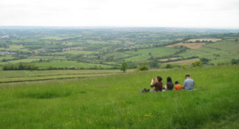 Group sitting on grass taking photos of the view