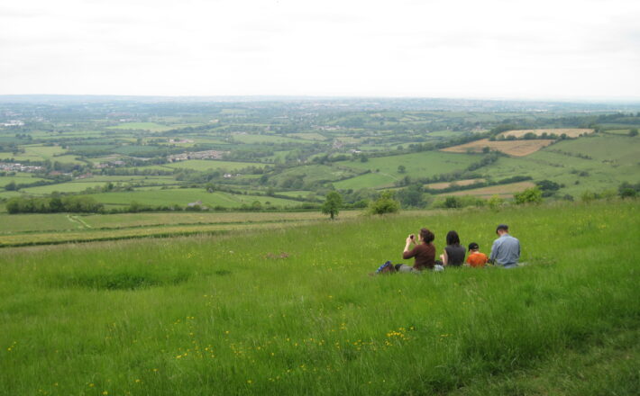 Group sitting on grass taking photos of the view