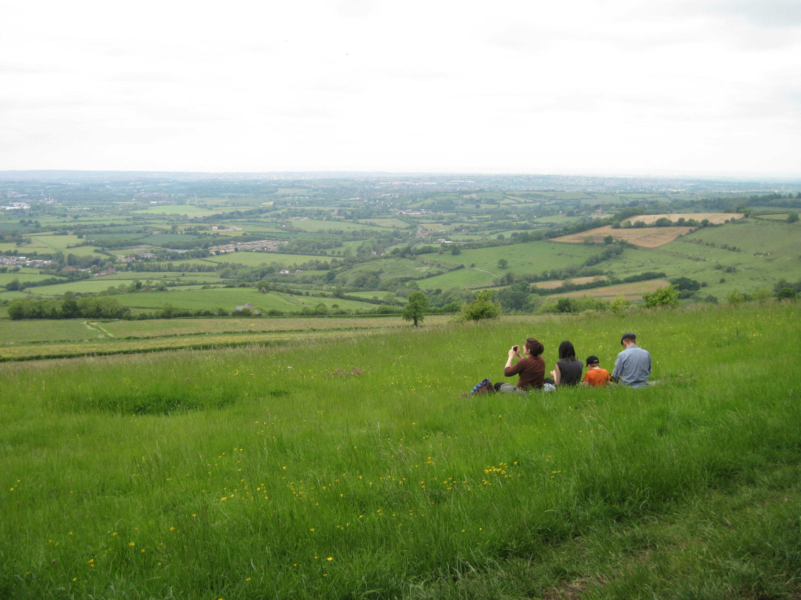 Group sitting on grass taking photos of the view